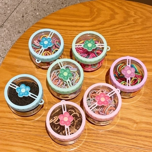 Colorful elastic hair bands for girls in a round floral box on a warm wooden table