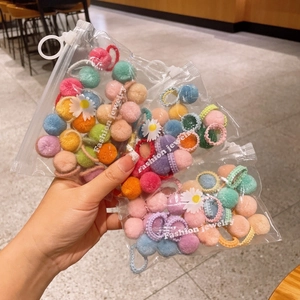 Macro shot of colorful plush ball hair ties in clear bags with white daisy charms