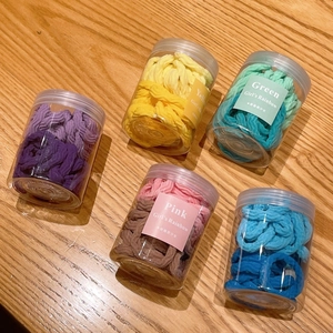 Détail de cinq pots d'élastiques à cheveux haute élasticité en diverses couleurs de macaron