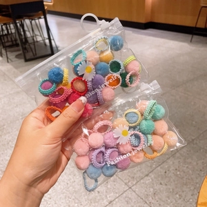 Detailed view of colorful plush ball hair ties set in a daisy patterned zipper pouch
