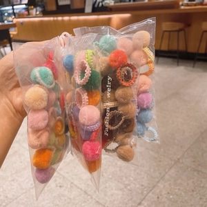 Close-up of assorted colorful plush ball hair ties in clear packaging for girls