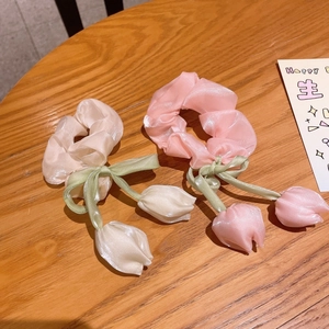 Détail de chouchous tulipe en organza rose et beige avec rubans verts sur bois