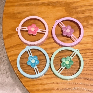 Close-up of colorful thumb hair ties with flower charms on a wooden surface