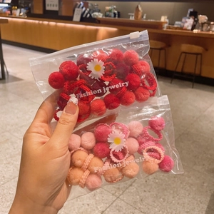 Close-up of assorted colorful plush ball hair ties in a cute daisy zip-lock bag for girls