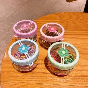Detailed view of four clear jars filled with colorful elastic hair ties for girls
