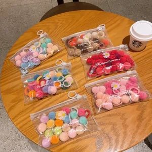Detail view of colorful plush ball hair ties in daisy printed transparent zip bags
