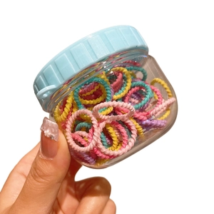 Colorful hair ties set for girls in a clear storage jar with blue striped lid