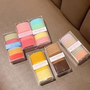 Macro view of multi-color high elasticity hair ties set in clear boxes on leather