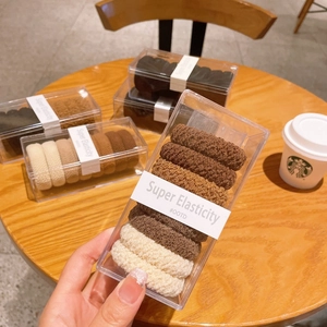 Gros plan d'élastiques à cheveux haute élasticité aux tons terre dans une boîte