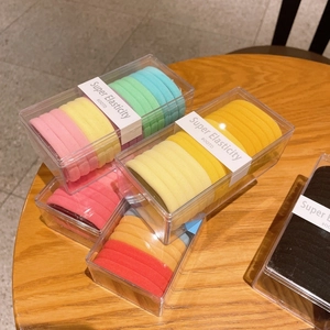 Macro shot of colorful seamless high elasticity hair ties in a clear rectangular plastic box