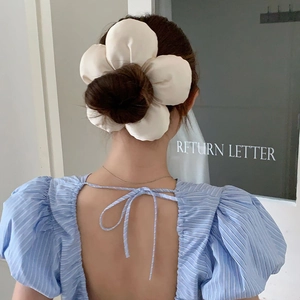 Oversized cream satin flower hair scrunchie shown in a stylish ponytail hairstyle