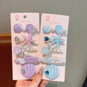Détail de barrettes sirène avec coquillages et étoiles sur carte rose