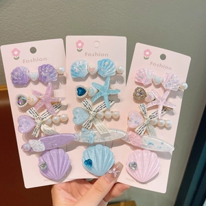 Détail d'un lot de barrettes sirène avec coquillages, perles et étoiles de mer sur rose
