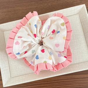 Détail du grand chouchou à motif de cœurs arc-en-ciel avec bordure plissée en organza rose