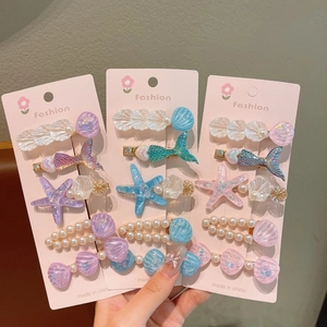 Détail de barrettes sur le thème marin avec queues de sirène roses et perles coquillages