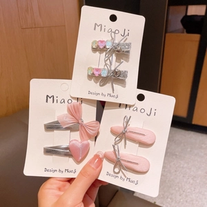 Dettaglio di fermagli per capelli argentati con fiocchi rosa e strass a cuore colorati
