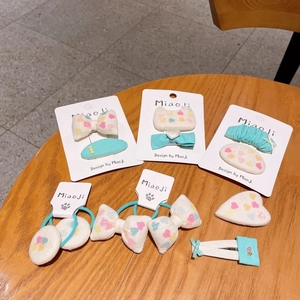 Detailed set of mint green and cream bow hair clips with heart patterns on a wooden table