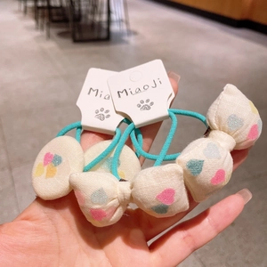 Detail of handmade bow and round elastic hair ties with colorful heart patterns