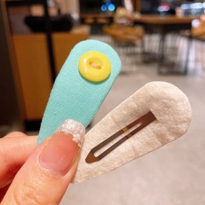 Detailed view of handmade mint green fabric hair clip and white felt duckbill clip