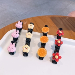 Détail de barrettes à cheveux mignonnes avec lapin et fruits sur plateau blanc