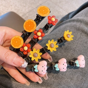 Détail de quatre barrettes colorées avec motifs de fruits et fleurs pour enfants