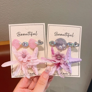 Detailed close-up of pink and purple starfish flower hair clips with pearls and crystals