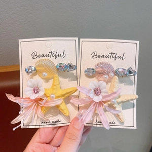 Detail of ocean-themed starfish shell clips with pearls and handmade fabric flowers