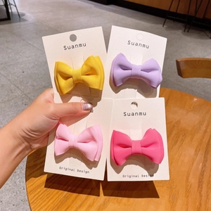 Close-up of four candy-colored bow hair clips on a display card in a cozy cafe setting
