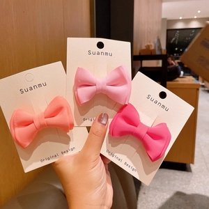 Detailed close-up of a three-piece matte bow hair clip set in various pink shades