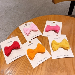 Detail of five colorful handmade fabric bow hair clips for kids on a wooden surface