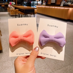 Detailed view of handmade dual-layer candy color fabric bow hair clips held by hand