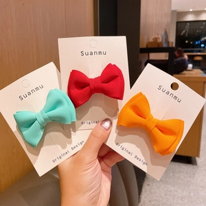 Three colorful handmade fabric bow hair clips in mint green, red, and bright orange colors