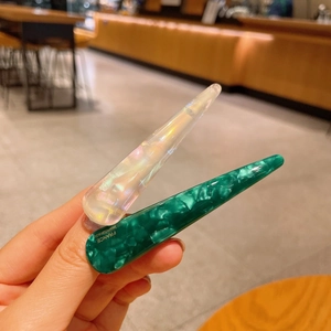 Elegant marble green and pearlescent white acetate hair clips shown in a hand