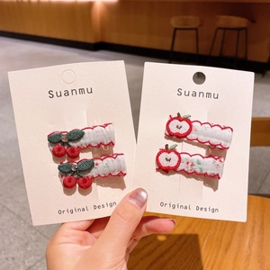 Close-up of cute embroidered cherry and apple hair clips on a floral fabric BB clip