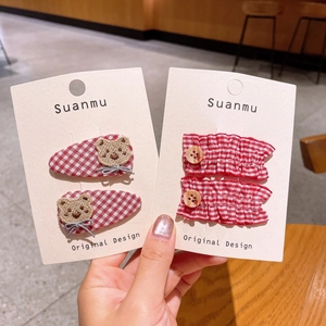 Detail of children's fabric hair clips with brown bear embroidery and red plaid patterns