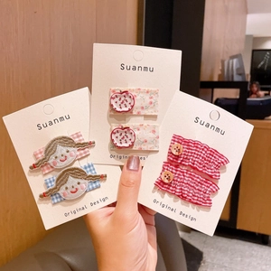 Detail of cute hair clips featuring embroidered girl, 3D red apple, and red plaid fabric