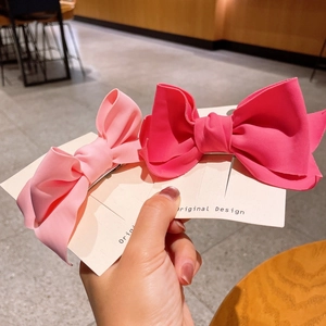 Close-up of pink and rose red fabric bow hair clips on a branded display card