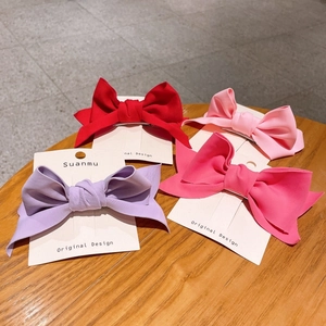 Close-up of four solid candy-colored fabric bow hair clips on branded display cards