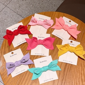Detailed overhead view of fabric bow hair clips in seven vibrant candy colors on wood