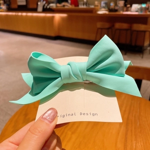 Detail of mint green fabric bow hair clip on original design card in cafe setting