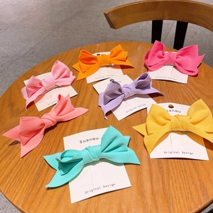 Detail view of 3D fabric bow hair clips in vibrant candy colors on wooden table