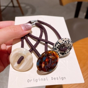 Close-up of three high-elastic hair ties with marble resin beads in warm earthy tones