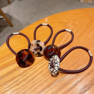 Detailed close-up of retro tortoiseshell acrylic charms on high elastic purple hair ties