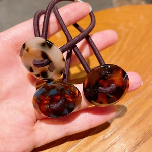 Close-up of three high-elastic purple hair ties with tortoiseshell pattern resin buckles
