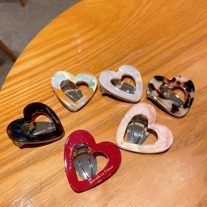 Set of six heart-shaped acetate hair clips with assorted patterns on a wooden surface