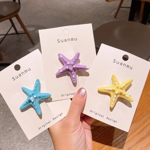 Dettaglio dei fermagli a stella marina in blu, viola e giallo su carta
