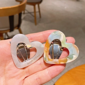 Detail view of heart-shaped acetate hair clips with marble texture and side branding