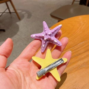 Dettaglio di fermagli per capelli a stella marina con texture viola e clip in metallo argento