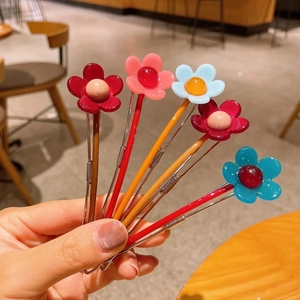 Dettaglio di cinque fermagli per capelli a forma di fiore in resina colorata