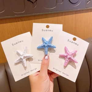 Tre fermagli per capelli a stella marina in bianco, blu e rosa su carta